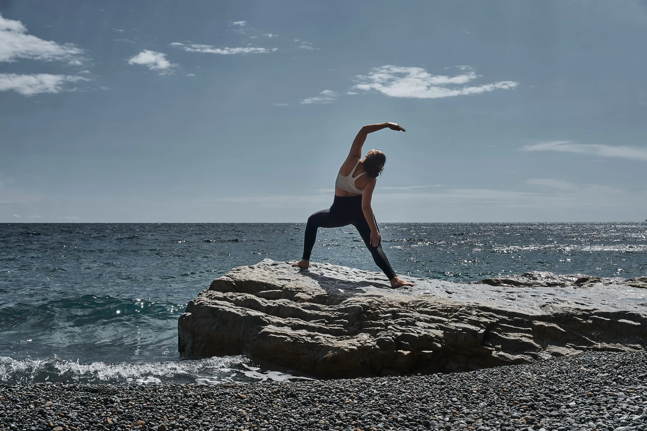 Kriegerin Asana auf einem Stein am Meer
